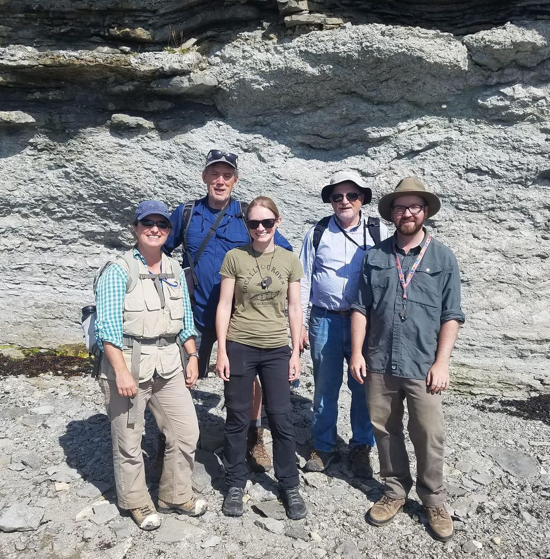 A group of people in front of a rocky cliff.