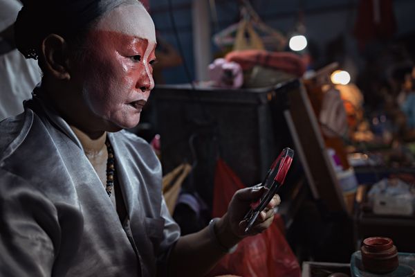 Chinese opera performer applying makeup thumbnail