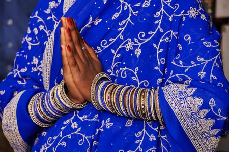 A woman performs the Namaskara gesture, a traditional Indian greeting with hands in front of chest and a slight bow.
