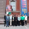 A group of teens stand in front of the Renwick Building for a group photo