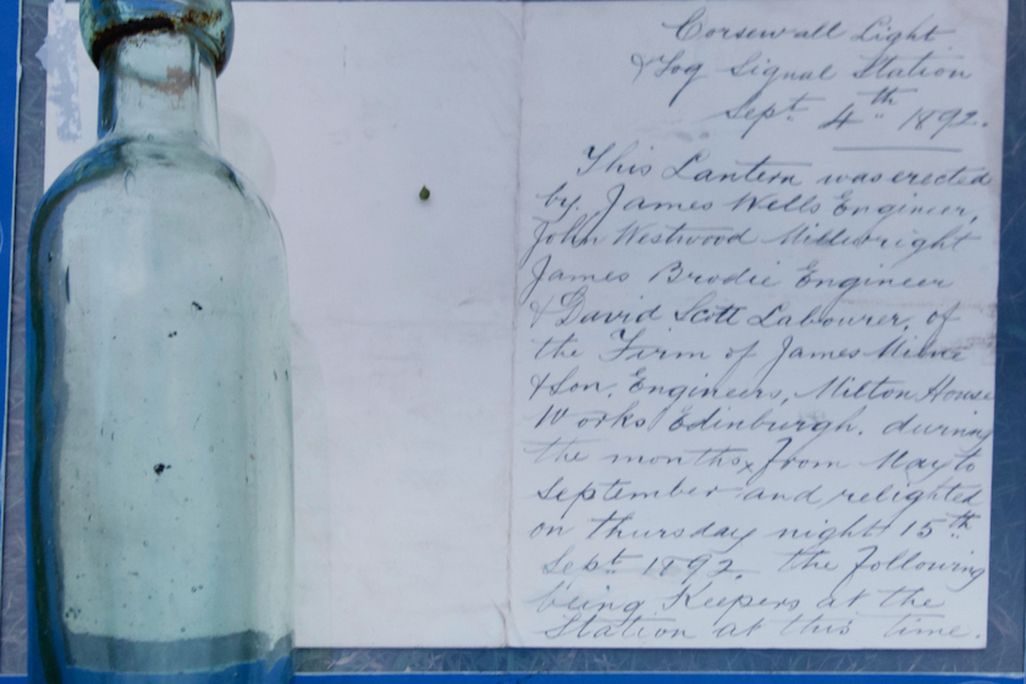 Glass bottle next to paper with cursive handwriting