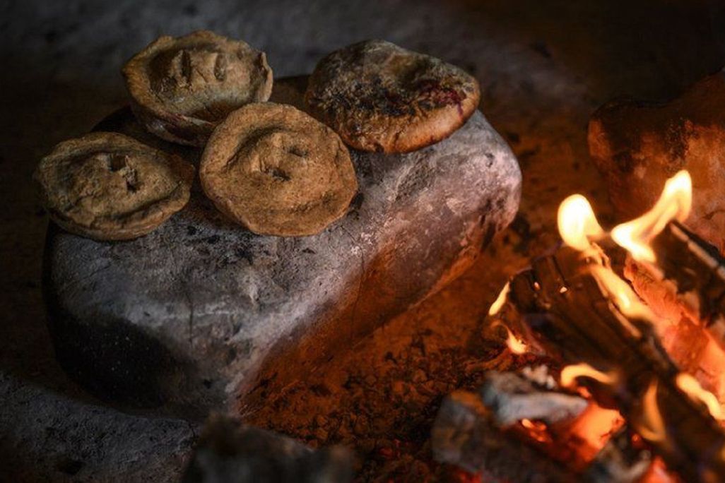 small pies cooking on hot stone by fire