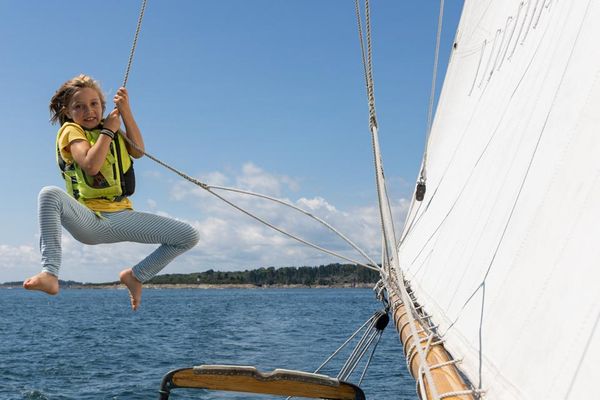 A child swinging on the rigging of a schooner while cruising mid-coast Maine thumbnail
