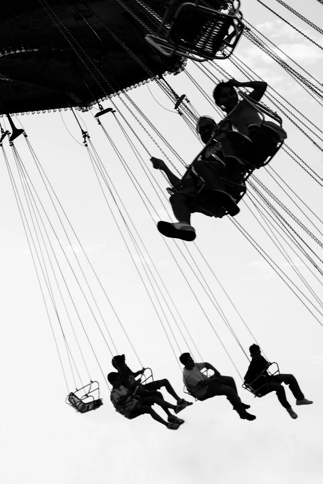 Black and white photo of people riding a swig ride