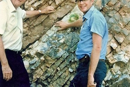 Luis and Walter Alvarez at the KT boundary.  Dinosaurs on the bottom right; little critters on the top left.