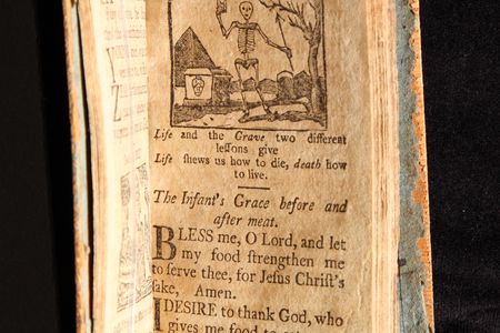 A page from a New England Primer printed in Massachusetts in 1811, with the text "Life and the Grave two different lessons give/Life shows us how to die, death how to live."