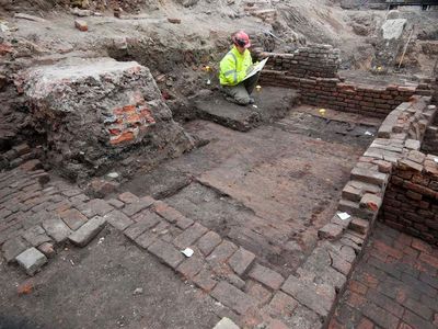 An archaeologist studies remains of the Curtain theater's foundations.