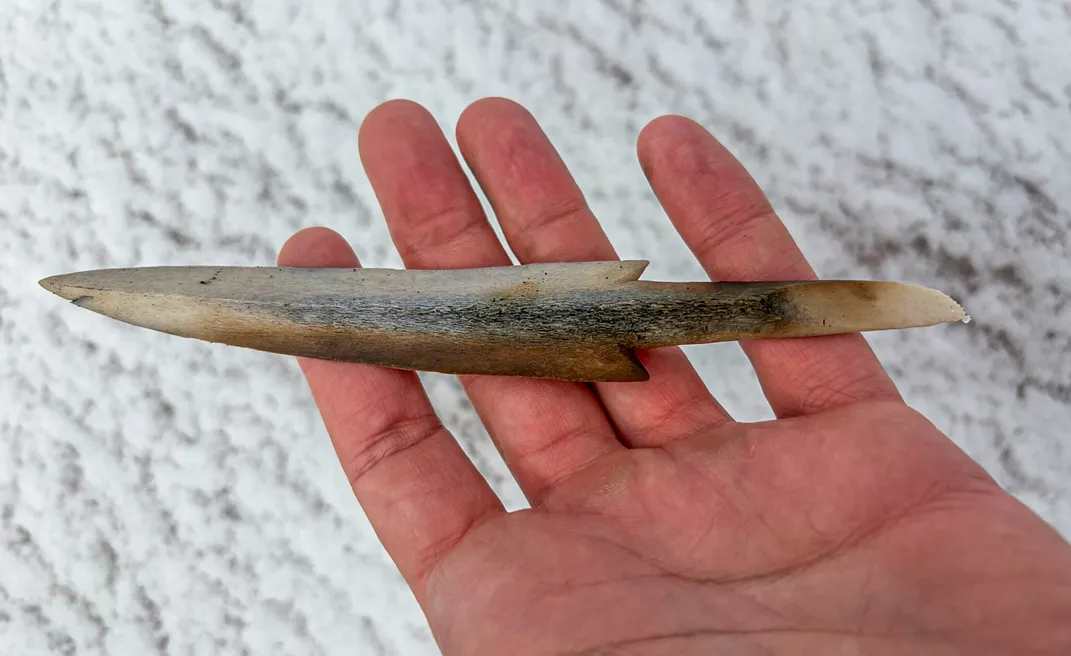 A bone arrowhead in a person's open palm