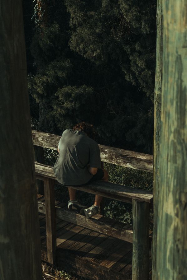 Person sitting on a wooden railing. thumbnail