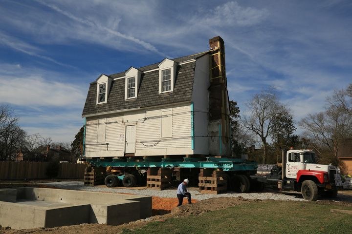White building on truck bed with man wearing white hard hat
