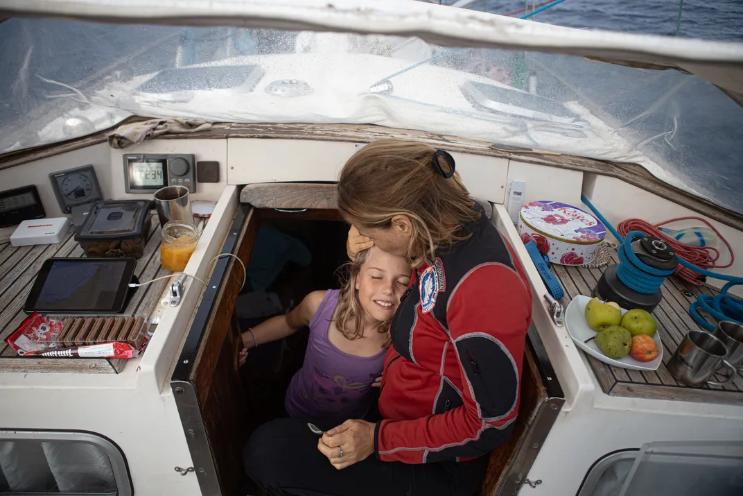 A father and daughter hug on boat in ocean