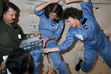 NASA Teacher-in-Space trainee Sharon Christa McAuliffe (right) and backup Barbara R. Morgan practice experiments during a zero-gravity training flight on October 16, 1985.