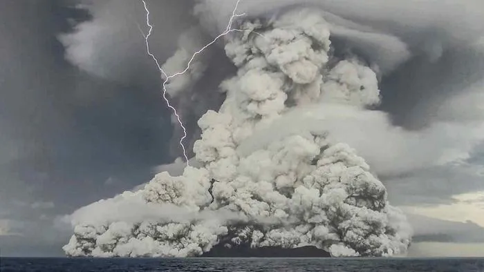 a screenshot from a video of the volcanic eruption shows a large plume of ash and gas as well as a y-shaped lightning bolt striking