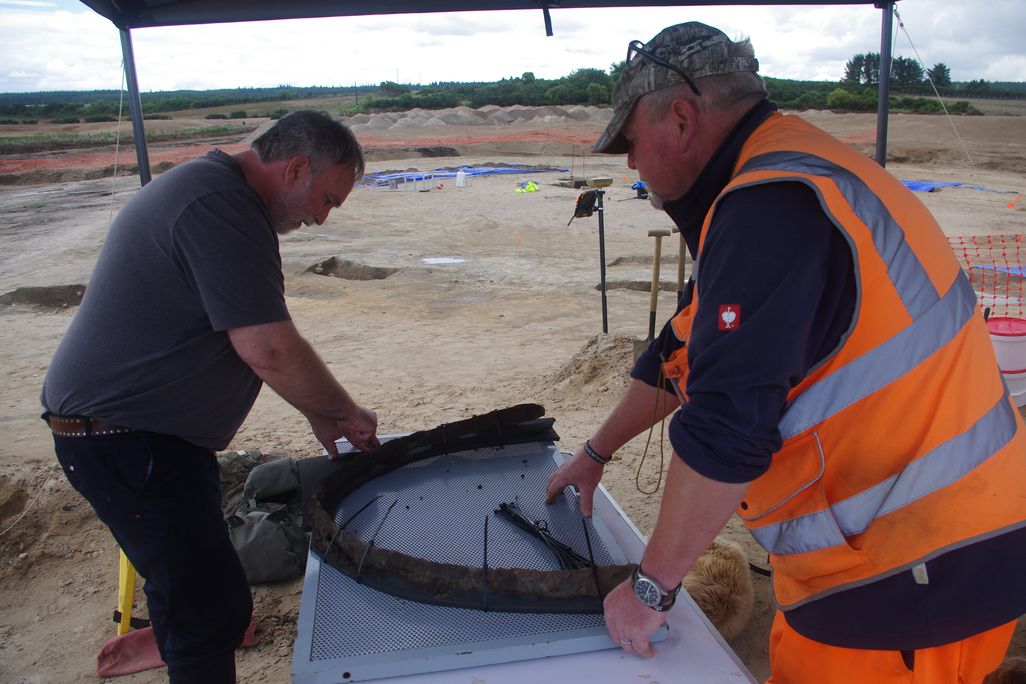 Two men looking down at artifact