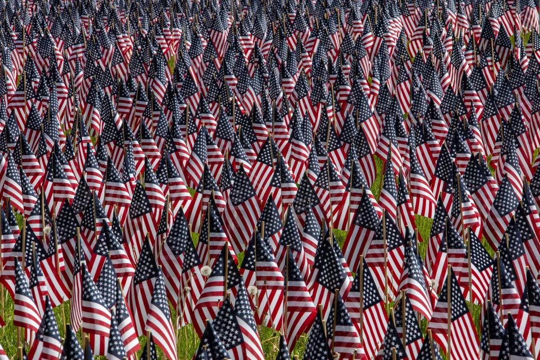 thousands of American flags stand in a field