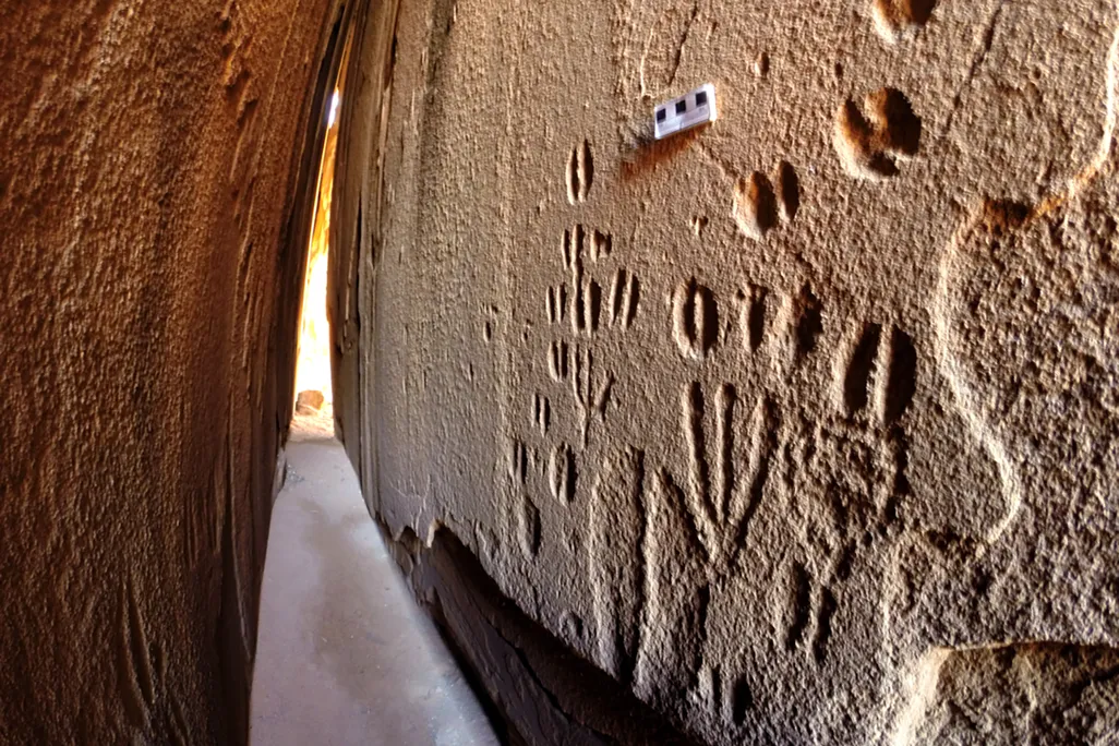 A narrow corridor between two slabs of rock with carvings on them