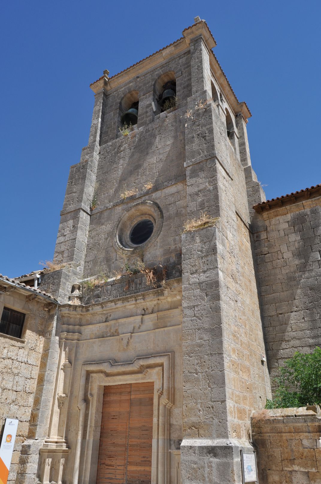 A view of the exterior of a belltower of light tan bricks