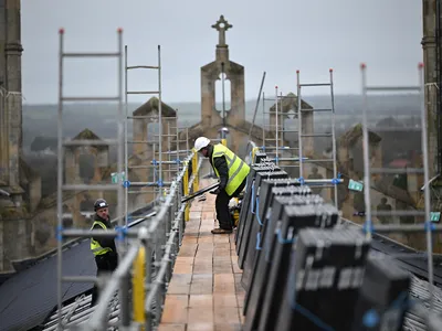 Workers install solar panels on the roof of King&#39;s College Chapel in Cambridge, England.