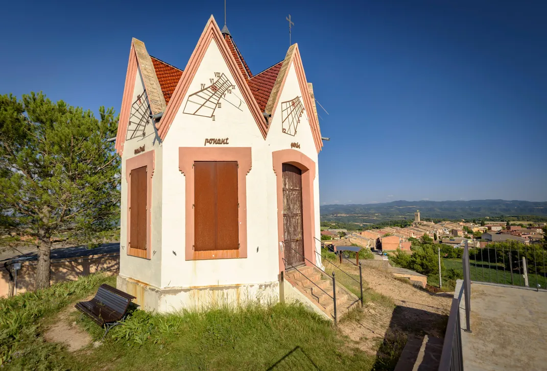 a small building sits on a hilltop overlooking a village