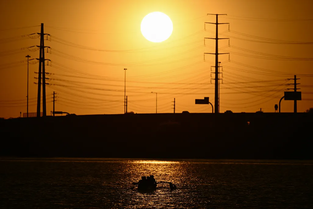 sun sets behind power lines in an orange sky