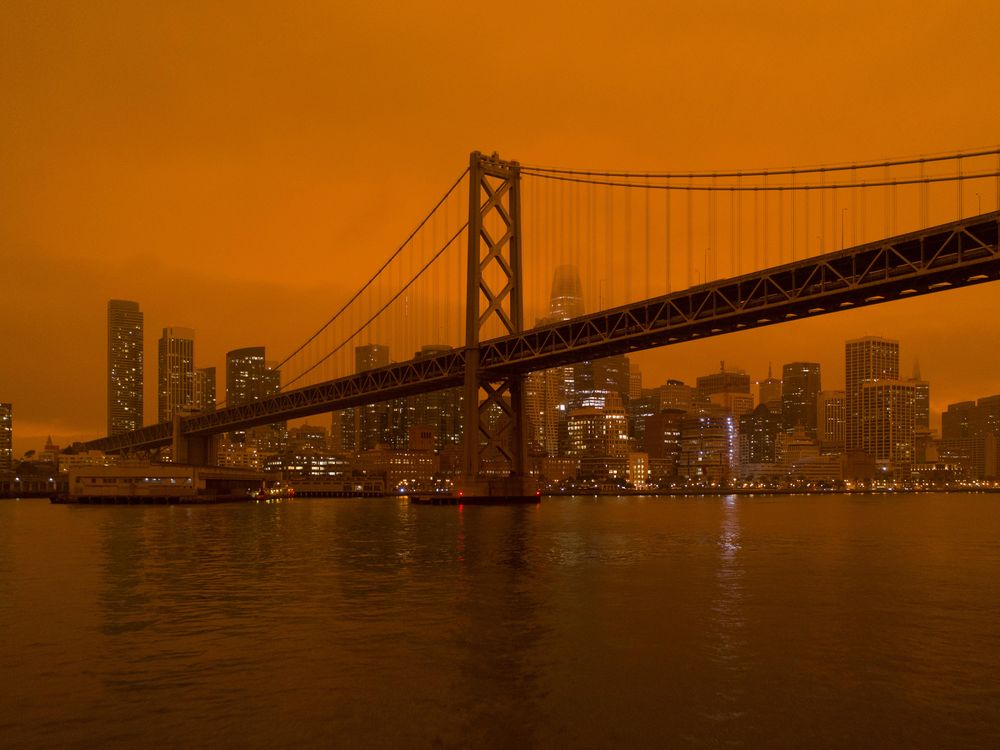 The Golden Gate Bridge and San Francisco skyline with a background of hazy, dark orange sky.