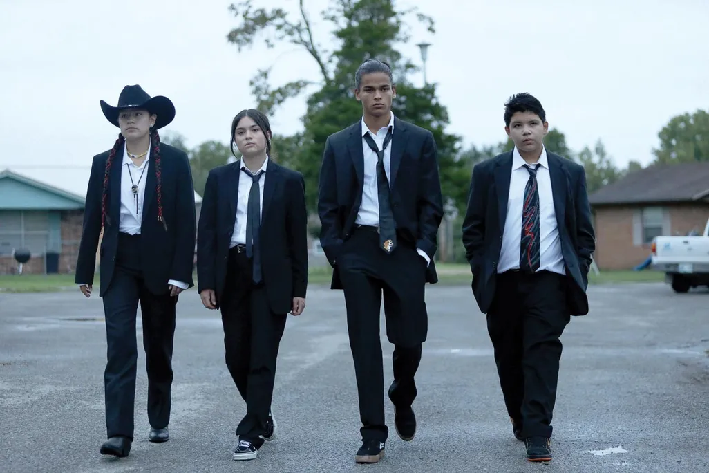 four Native American teenagers in black suits walking