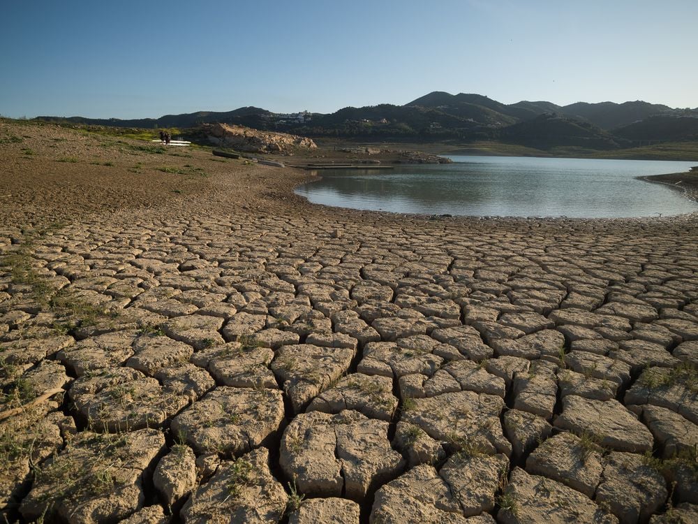 dry, cracked ground on the shores of a heavily receded reservoir in eastern Spain.