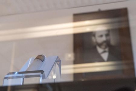 A picture of Friedrich Miescher hangs behind a test tube with isolated nucleic acid from salmon sperm from the original holdings in the museum of the University of Tübingen.
