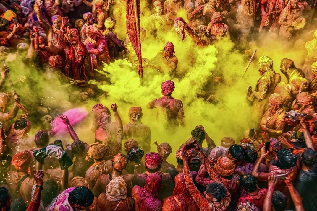 a yellow powder is thrown into a large crowd during Holi Festival