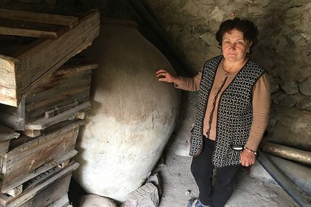 Asli Saghatelyan stands next to her father-in-law’s 240-gallon karas, a clay vessel traditionally used in Armenia, until recently, for storing and fermenting homemade wine.