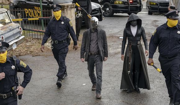 In a scene from the HBO series, Tulsa’s masked police force prepares for a raid. Detective Wade Tillman (known as “Looking Glass”) is played by Tim Blake Nelson. Detective Angela Abar (known as “Sister Night”) is played by Regina King (Mark Hill for HBO).