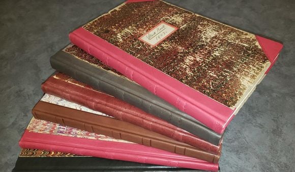 Stock books with marbled covers and leather bindings in various color fanned out.