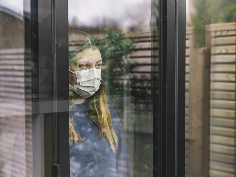 Woman wearing mask stares out a window