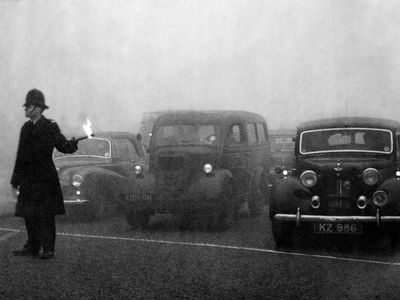 A policeman uses flares to guide traffic during the Great Smog of 1952.