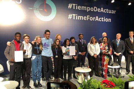 Sara Cognuck (center) shows the Declaration on Children, Youth and Climate Action.