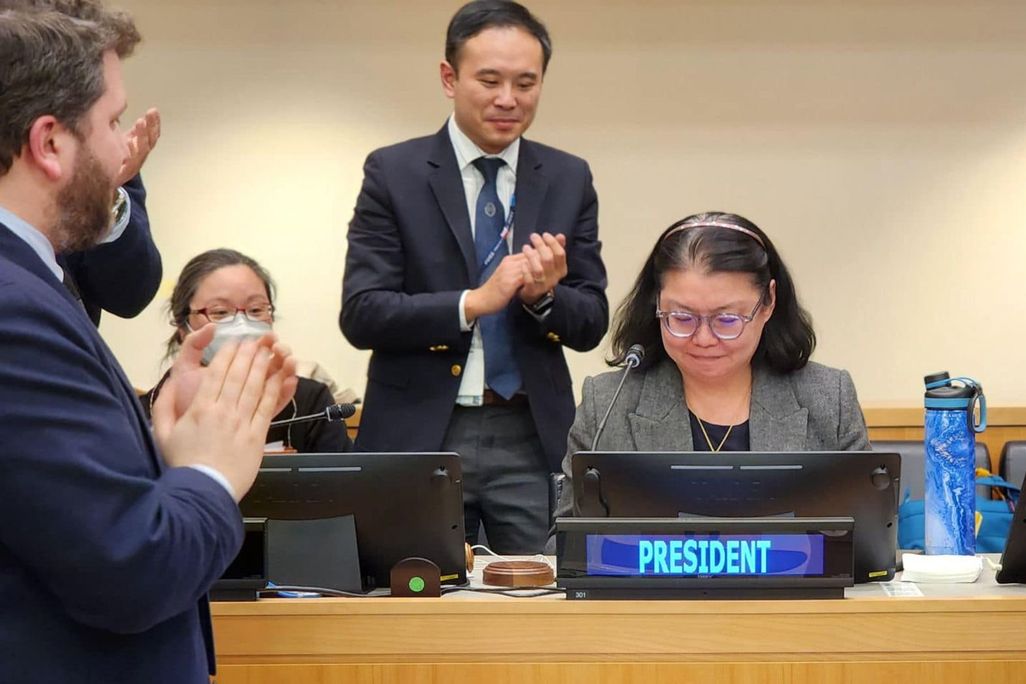 woman smiles at desk as people applaud