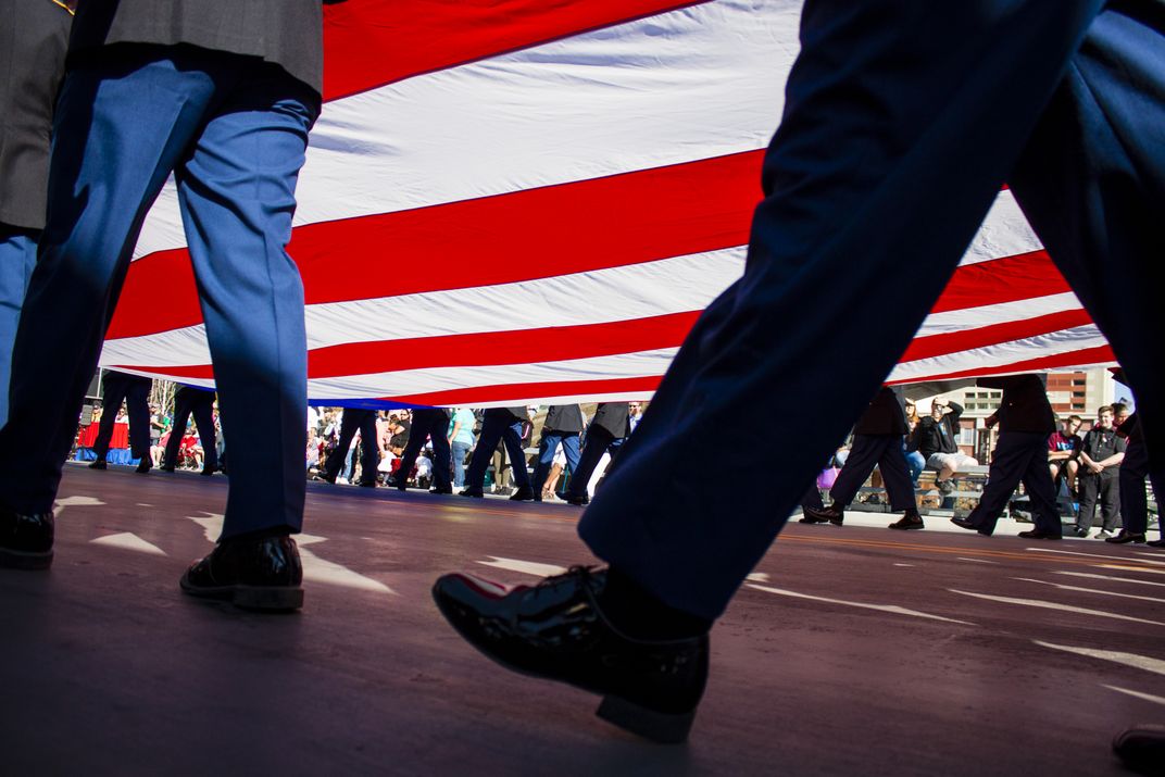 an unfurled American flag is carried during a parade
