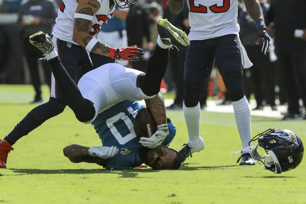 A football player being tackled with his helmet popped off and his head on the ground