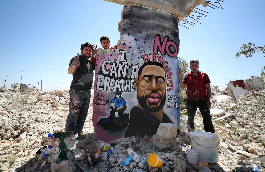 Artists pose with their mural in the Binnish district of Idlib province, Syria