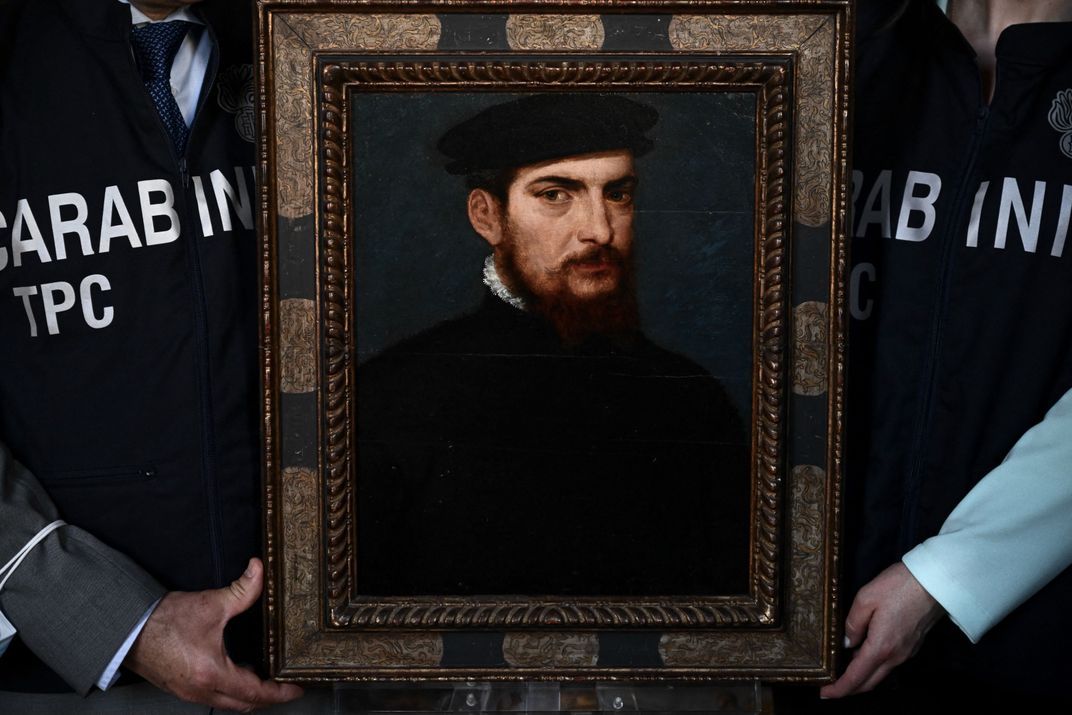 Italian art police hold up a recently recovered Titian portrait of a bearded man