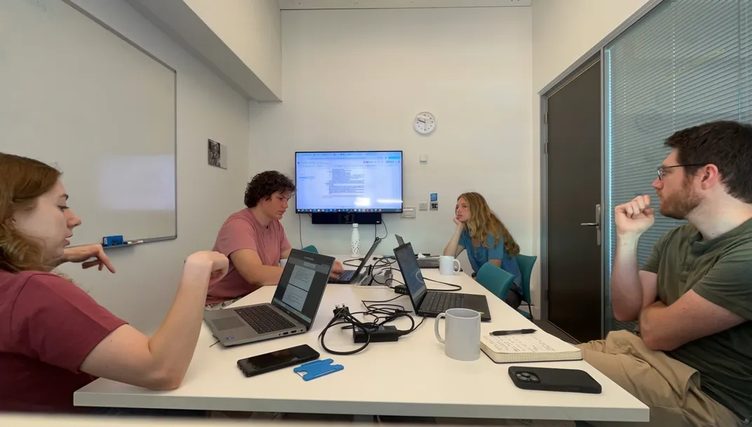 Four postdocs sit in a conference room