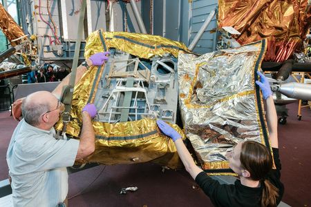 Conservators remove an original flight blanket, revealing a space for storing the supplies astronauts used to explore the lunar surface, such as cameras, geology equipment, and gear for an extended lunar stay.