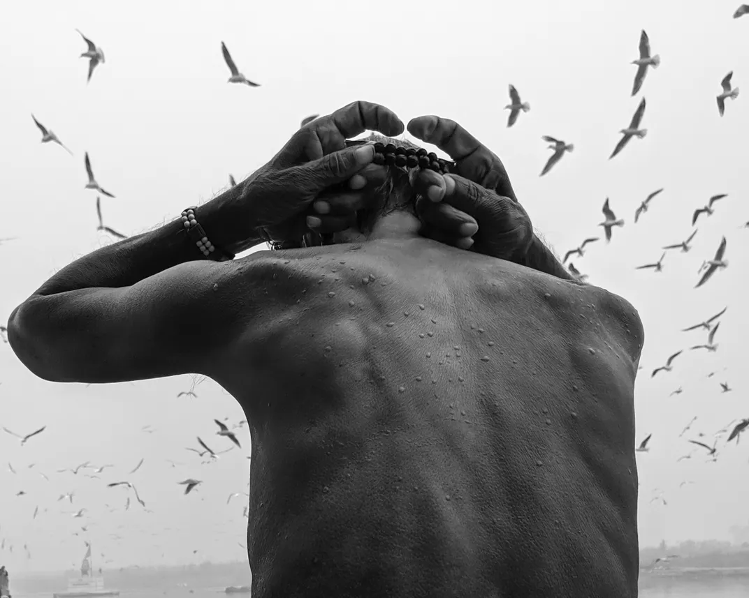 Man putting on bead garland with seagulls in background