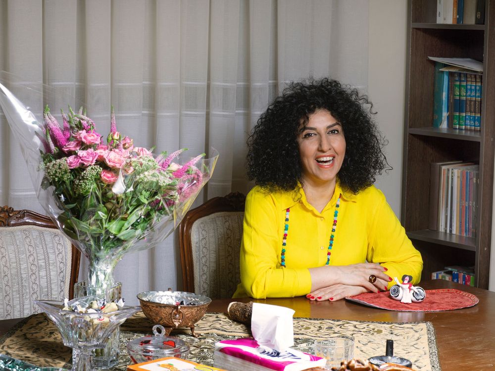 Smiling woman wearing a yellow shirt next to a bouquet of flowers