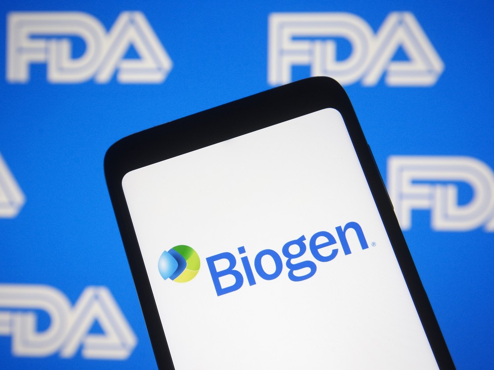 A phone screen shows the Biogen logo in front of a background with the FDA logo 