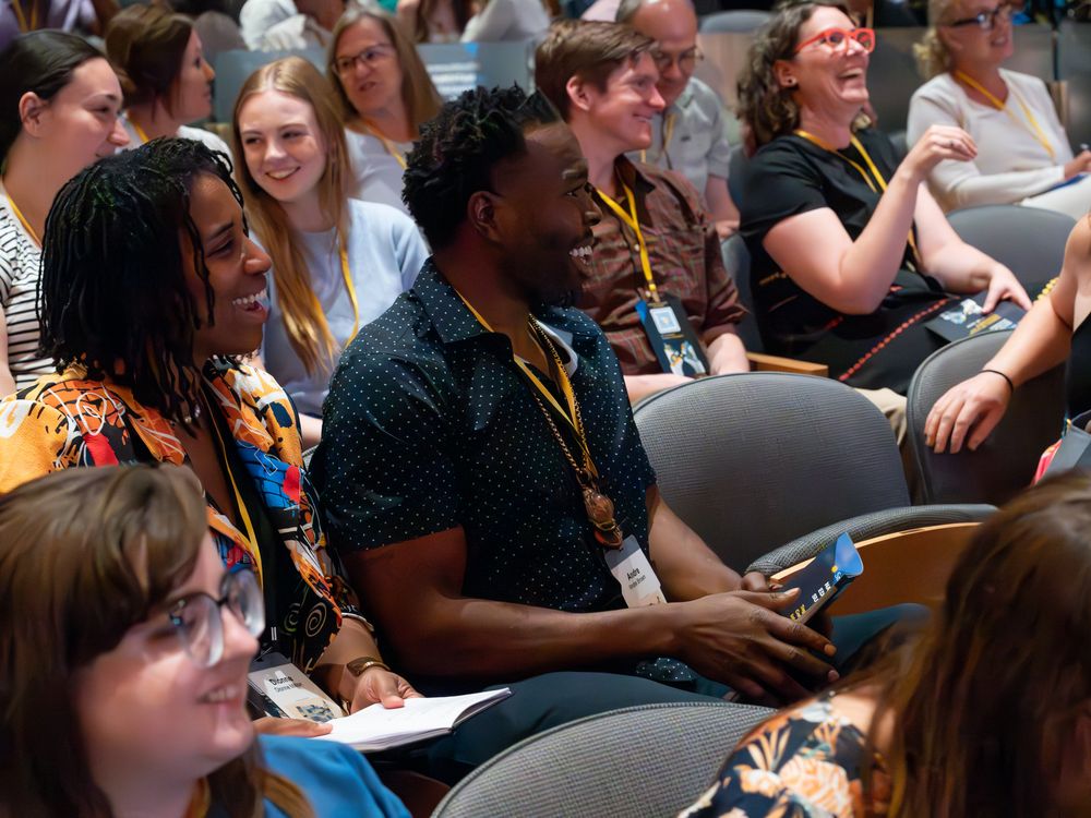 A group of men and women are in an audience turning and talking to each other with smiles