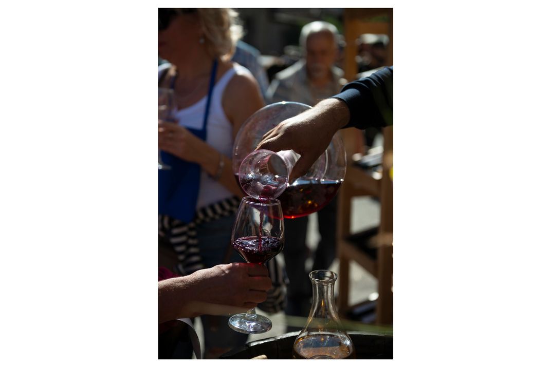 One person pours a glass of wine into a wine glass held by another person.