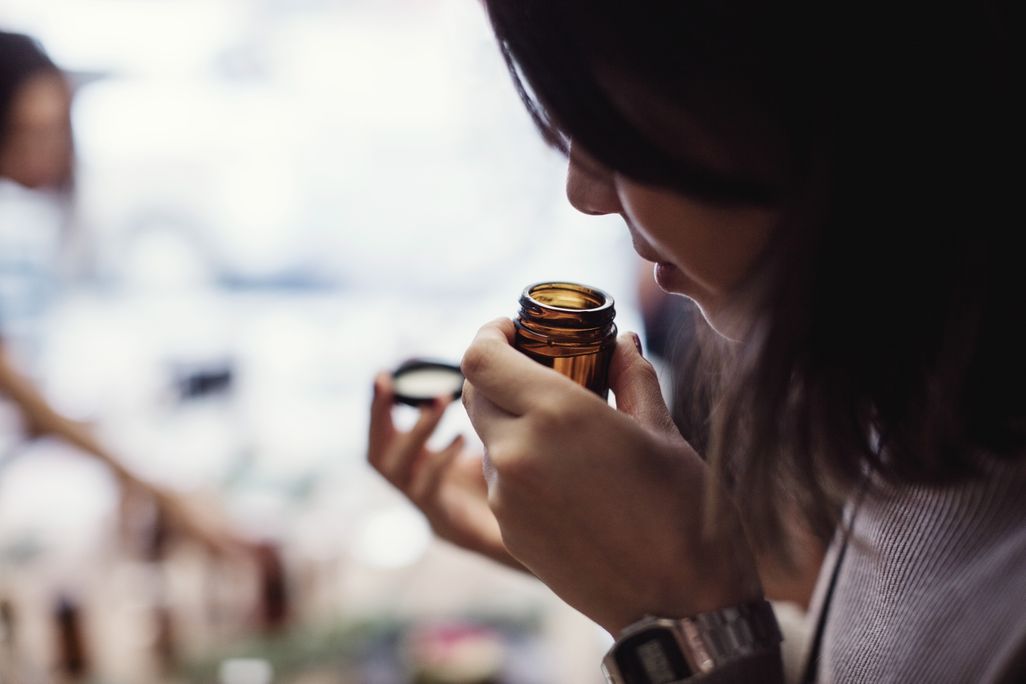 Woman smells open bottle close to her nose