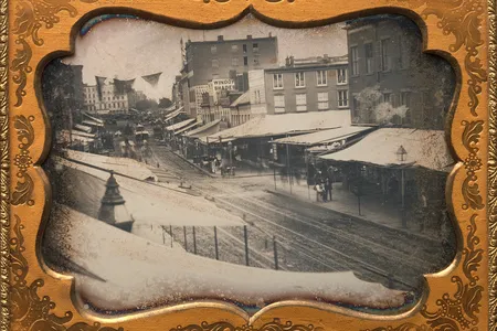 Shade-protecting overhangs known as awnings line a street in New York City in the 1850s.