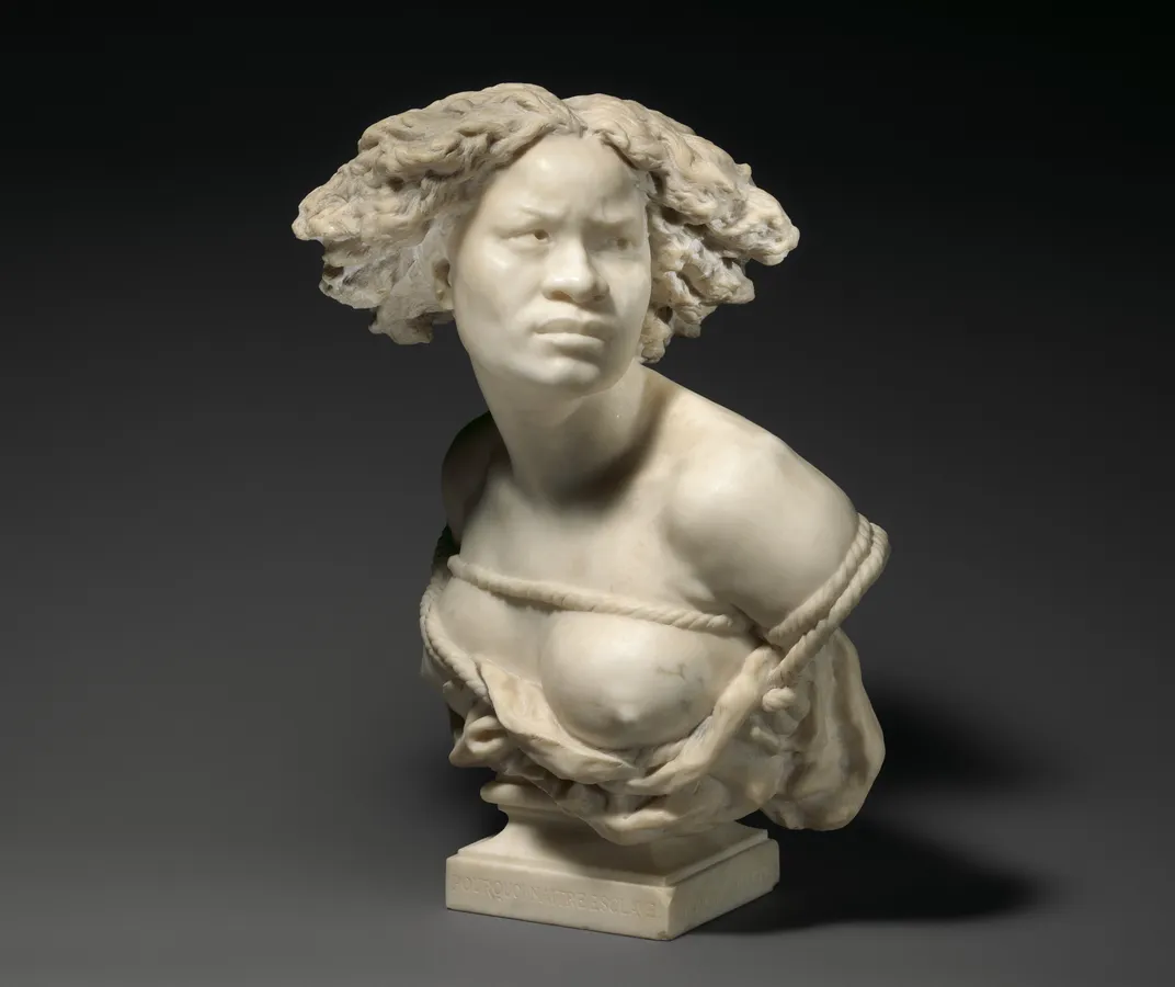 A white marble bust of a woman with curly hair and defiant expression, bound with ropes and wearing a cloth with breasts exposed